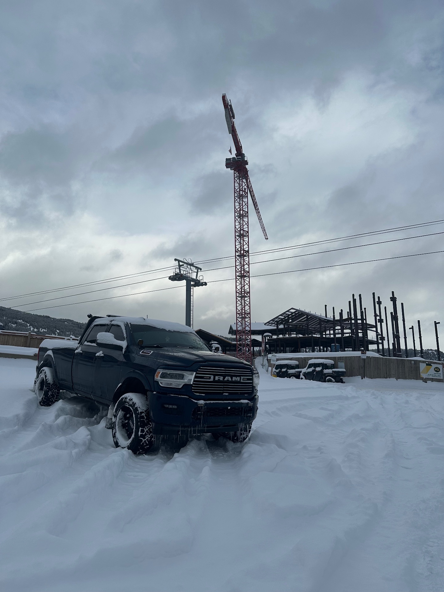 Driftwood truck on site beside a tower crane at a mountain construction project