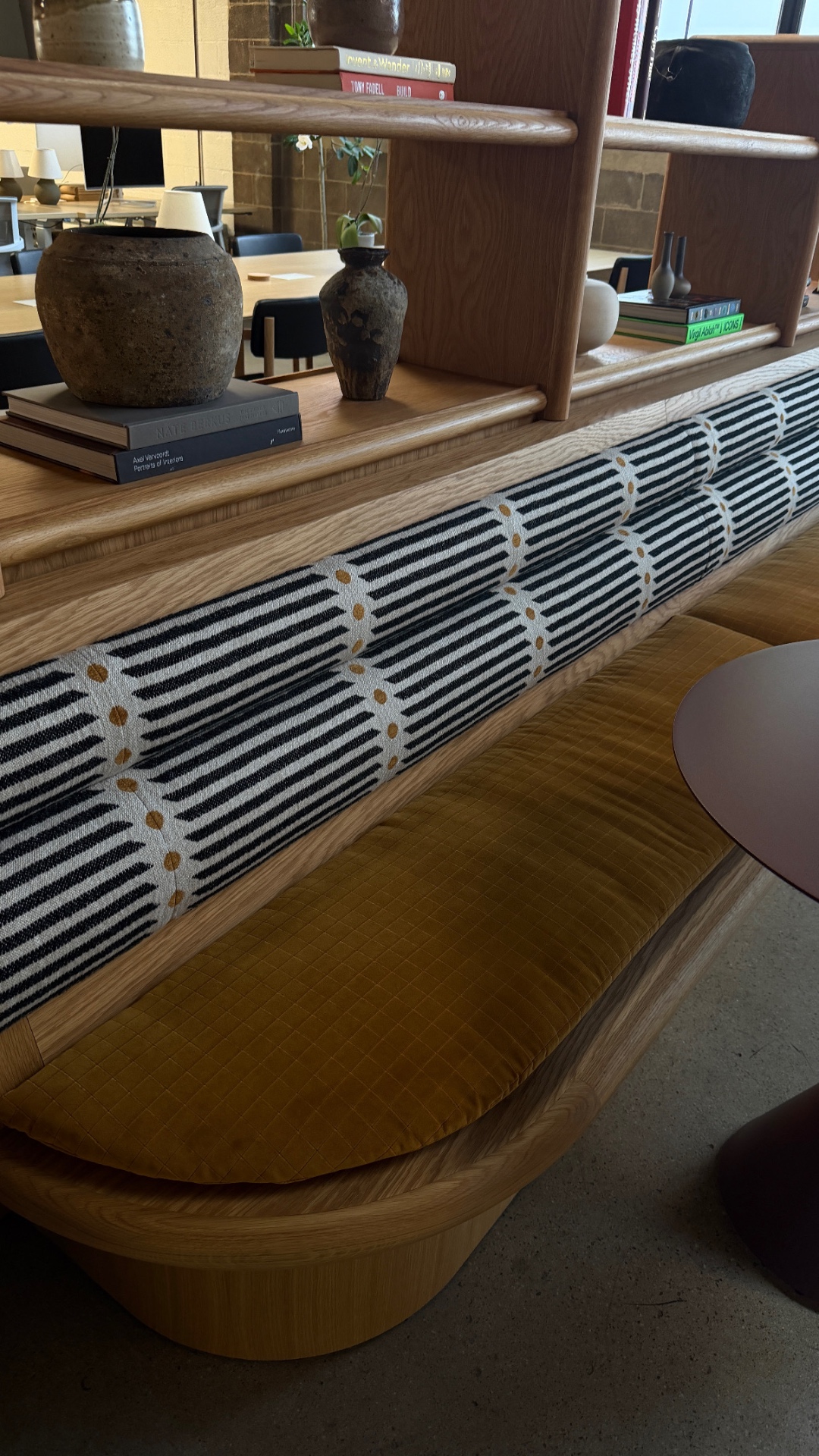 Custom oak banquette at Intro with quilted ochre cushions and striped bolster